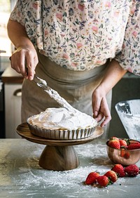 Woman spreading meringue to lemon pie