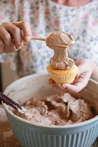 Woman adding chocolate frosting to cupcake food photography recipe idea
