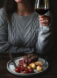 Woman drinking red wine with a steak