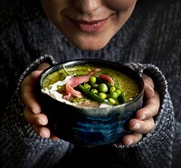 Woman holding a bolw filled with green pea soup
