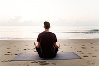 Man practicing yoga on the beach