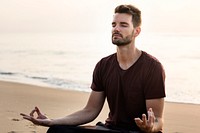 Man practicing yoga on the beach