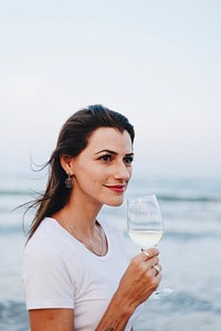 Woman drinking a glass of wine by the beach