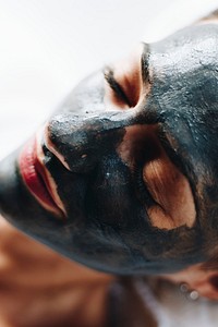 Woman relaxing with a charcoal facial mask