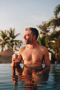 Handsome man having a glass of wine in the pool