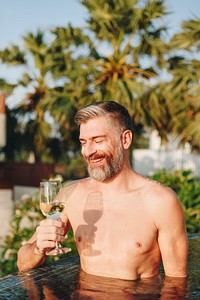 Handsome man having a glass of wine in the pool