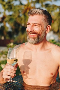 Handsome man having a glass of wine in the pool