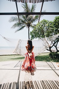 Woman sitting in a hammock by the beach