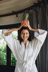 Woman in a bathrobe holding a pineapple