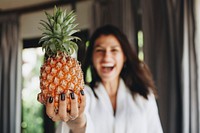 Woman in a bathrobe holding a pineapple