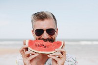 Mature man eating watermelon at the beach