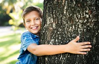 Boy hugging a big tree in the park