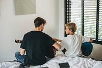 Siblings playing guitar in the bedroom