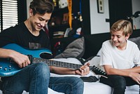 Boys playing the guitar in bed