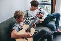Brothers hanging out on the couch playing guitar