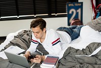 Teenage boy on his bed using his phone and laptop simultaneously