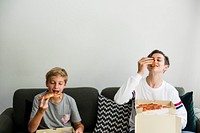 Brothers eating pizza on the couch