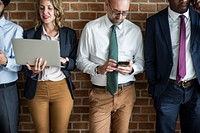Business people standing in a row using electronic devices