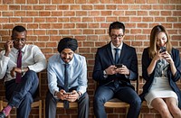 Business people sitting in a row using smartphones