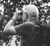 Mature man watching birds through binoculars