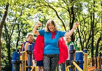 Happy seniors wearing superhero costumes at a playground