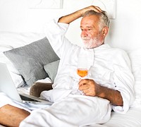 Senior man having prosecco in bed