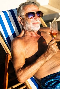 Senior man chilling and drinking wine on deck chair