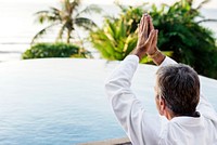 Senior adult practicing yoga by the pool