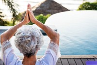 Senior adult practicing yoga by the pool