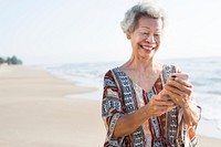 Senior Asian woman using a phone at the beach