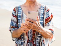Senior Asian woman using a phone at the beach