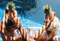 Couple holding pineapples above their heads