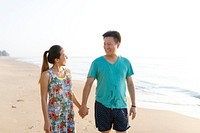 Asian couple holding hands at the beach