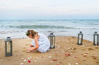 Young girl collecting flower petals on the beach