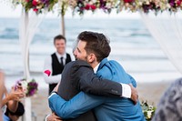 Groom getting a hug at the beach wedding