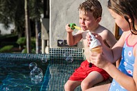 Kids blowing bubbles by swimming pool