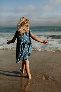 Little girl walking barefoot at the beach
