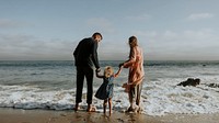 Parents holding daughter's hand at the beach