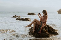 Woman taking photos with her phone on the beach