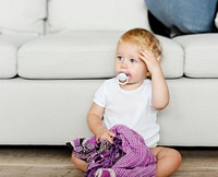 Baby with a pacifier and a blanket on the floor