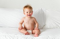 Smiling baby sitting on the bed