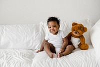 Baby with a teddy bear on the bed