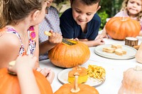 Young kids carving Halloween jack-o'-lanterns