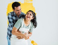 Cheerful couple painting the walls yellow