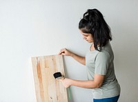 Woman coating a wooden plank with lacquer