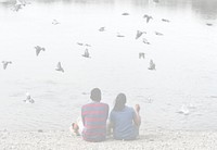 Couple sitting by the lake with birds flying