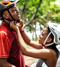 Woman fastens a bike helmet for her boyfriend
