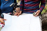 Trekking couple using map and compass in a forest