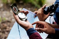 Trekking couple using map and compass in a forest