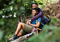 Trekking couple resting on a tree trunk